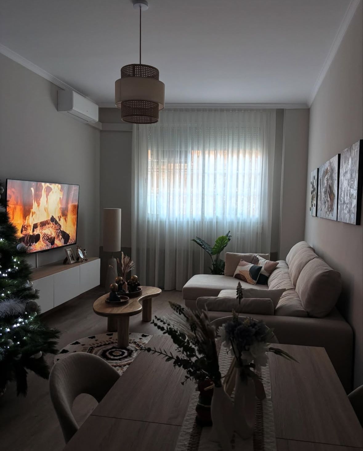 Salón de reforma integral con sofá beige, mesa de madera y luz natural.